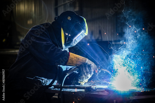 Skilled Welder in protection at Work with Sparks Flying in Industrial Workshop photo