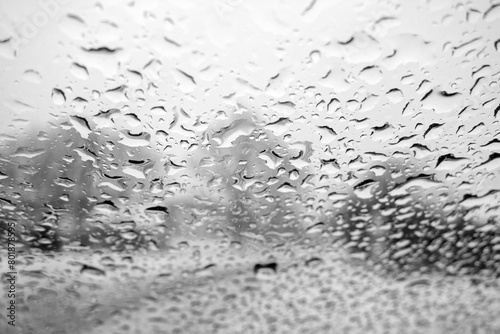 View on winter city through wet windshield with rain drops. Black and white