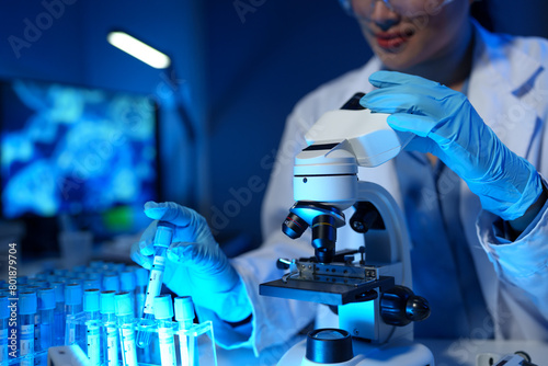 Scientists use scientific test tubes with records of chemicals or drugs being tested and examined under a microscope in a science laboratory for biology, biotechnology, medicine.