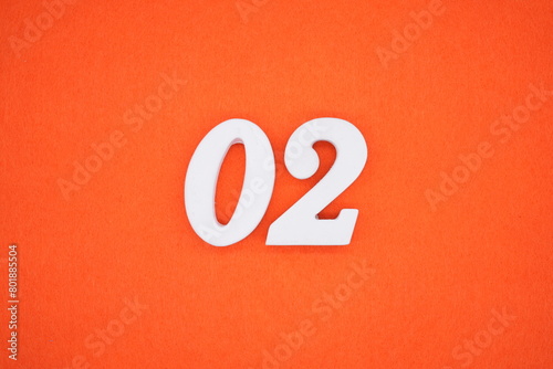 The number 02 is made from white painted wood placed on a background of orange paper.