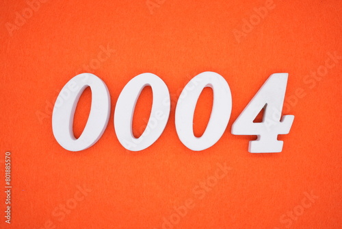 The number 0004 is made from white painted wood placed on a background of orange paper.