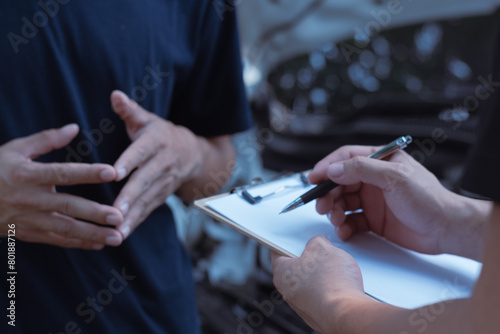 Automobile repairman writing job checklist on clipboard