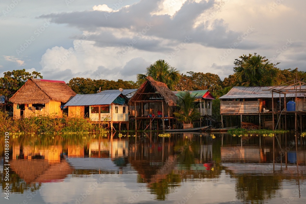 Sunset over Amazon Jungle Village, Sunbathed Houses in front of Sleepy River - Peru Stock Photo 