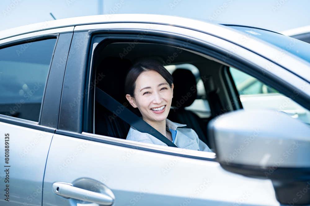 車に乗った作業着を着た笑顔の日本人女性