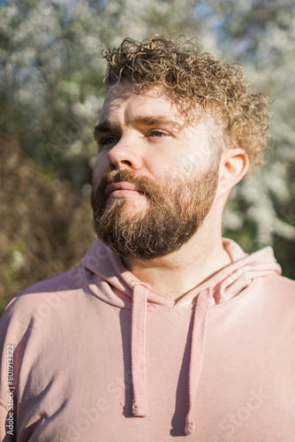 Man with beard and mustache near sakura flowers or blooming spring tree. Soft and gentle concept. Bearded man with stylish haircut with flowers on background, close up. Hipster near branch of bloom