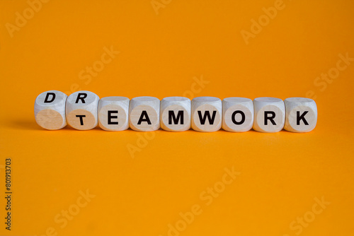 Teamwork and dream work symbol. Turned wooden cubes and changes the word teamwork to dreamwork. Beautiful orange background. Concept of well-coordinated team work in business photo