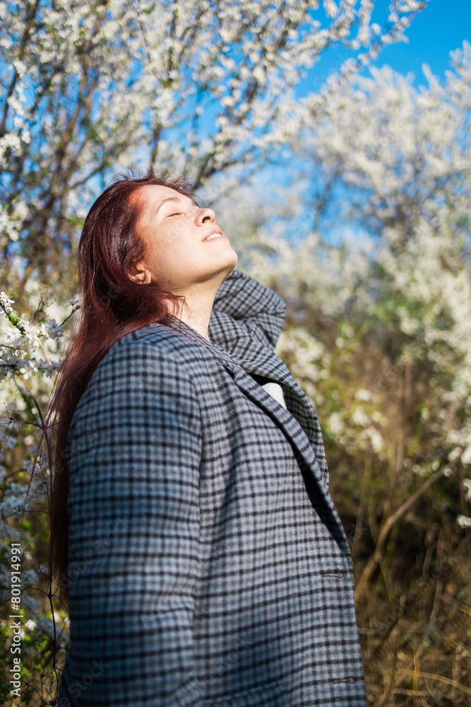 Beautiful red-haired woman enjoying smell in a flowering blooming spring garden. Spring blossom. Beautiful red-haired woman enjoying smell in a flowering blooming spring garden. Spring blossom.