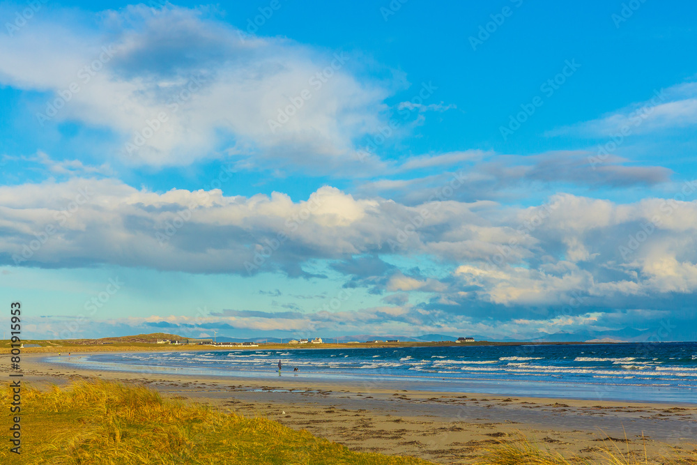 Gott Bay, Isle of Tiree, Inner Hebrides, Scotland in Springtime with whitewashed cottages, blue sky, machair, and a choppy sea. Hoirzontal.  Space for copy