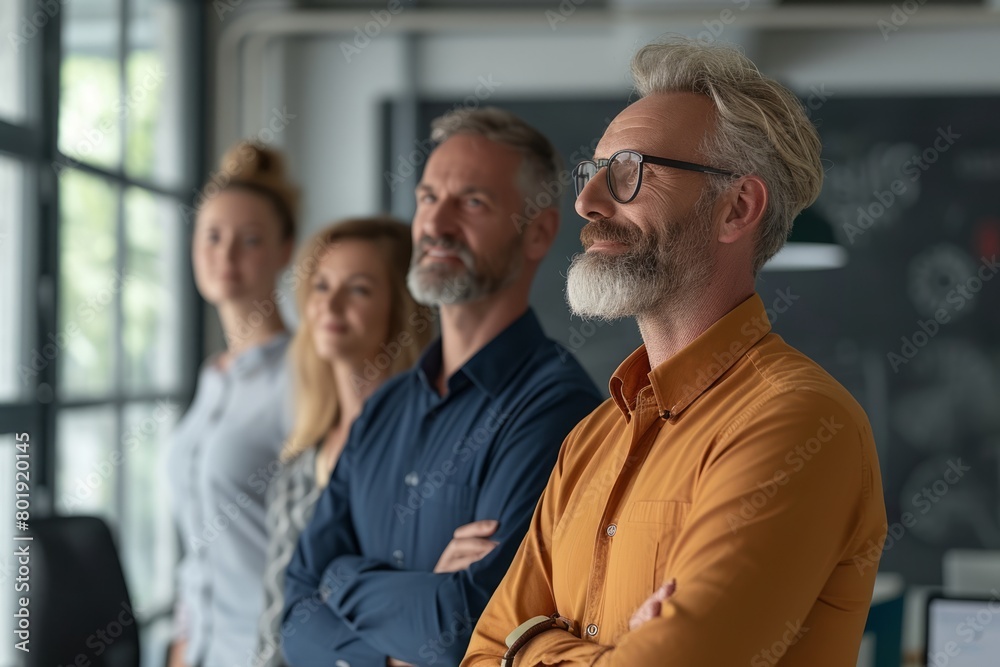 Portrait of confident mature businessman with colleagues in background at office.