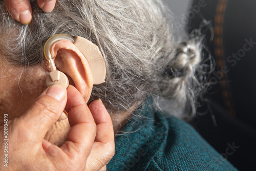 Caucasian elderly woman with a hearing aid in ear.