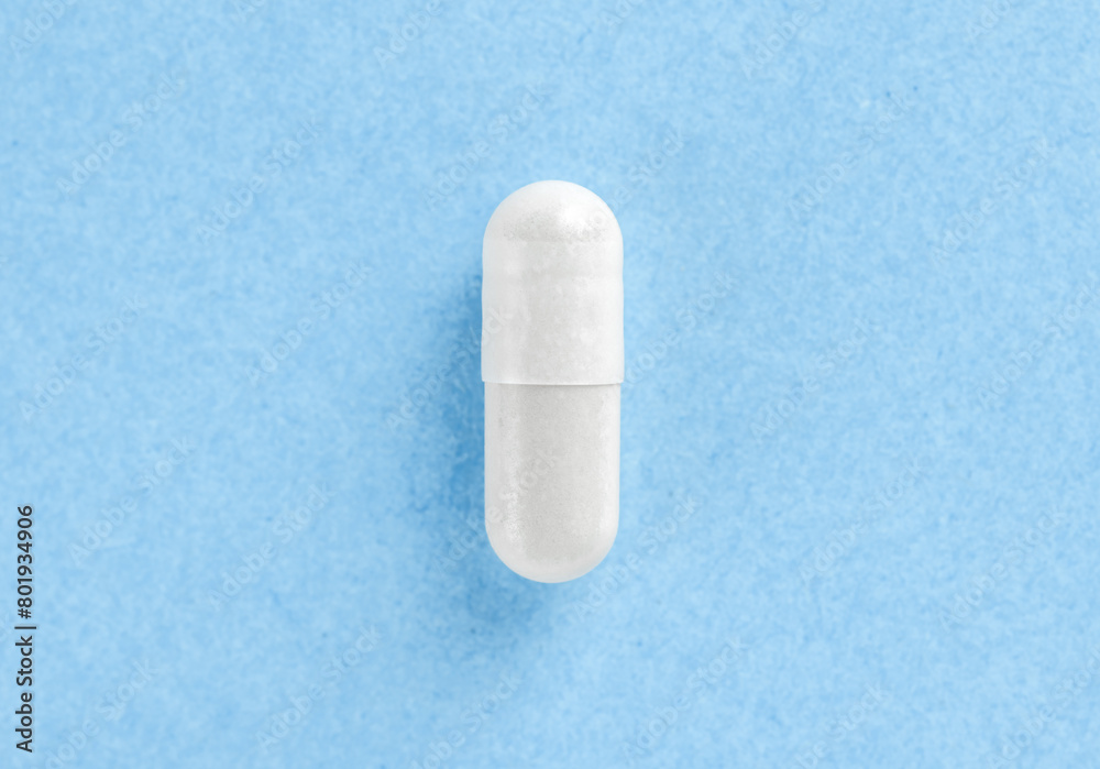 White two-piece hard starch capsule on blue background with copy space. Health concept. White two-piece hard starch capsule on blue background with copy space. Health concept.