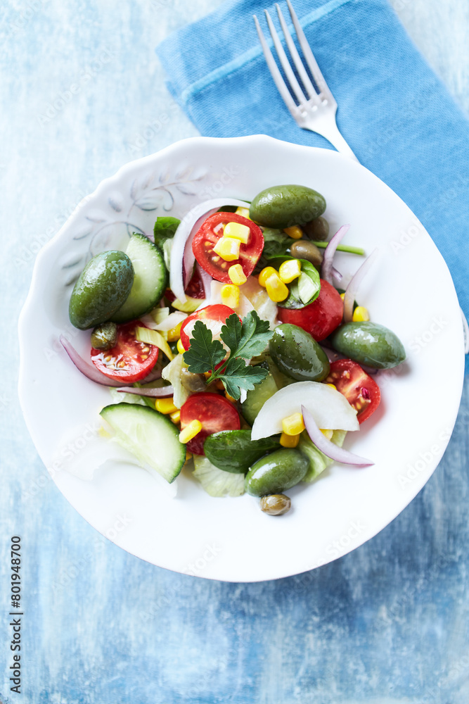 Simple Salad with Green and Kalamata Olives, Cucumber, Cherry and marinated Tomatoes, Capers and Jalapeno Pepper. Bright wooden background. Top view.