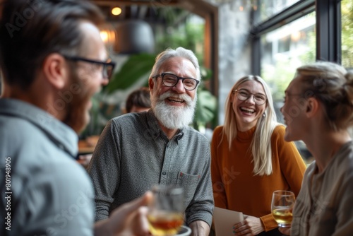 Cheerful senior man talking to his friends and drinking beer in cafe