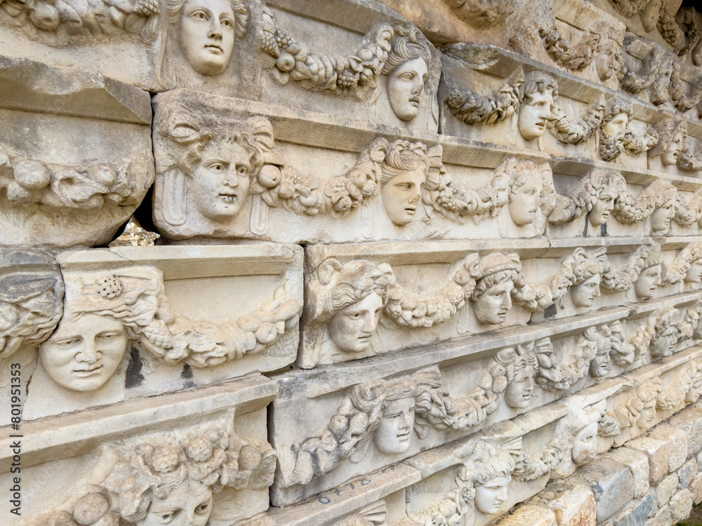 A detailed view of a sculptural frieze at Aphrodisias, showcasing a variety of carved classical faces adorned with garlands.