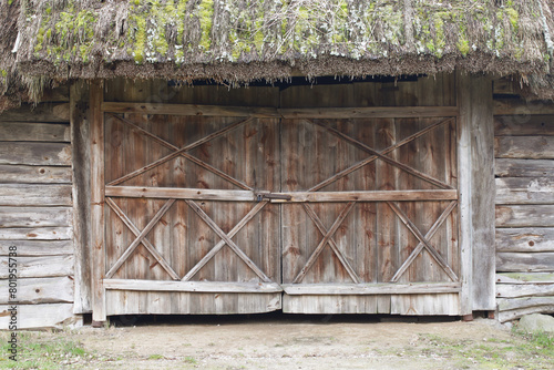 Grunge wooden barn door. Rustic vintage desk construction background. Countryside architecture texture. Village building entrance. Thatched roof.