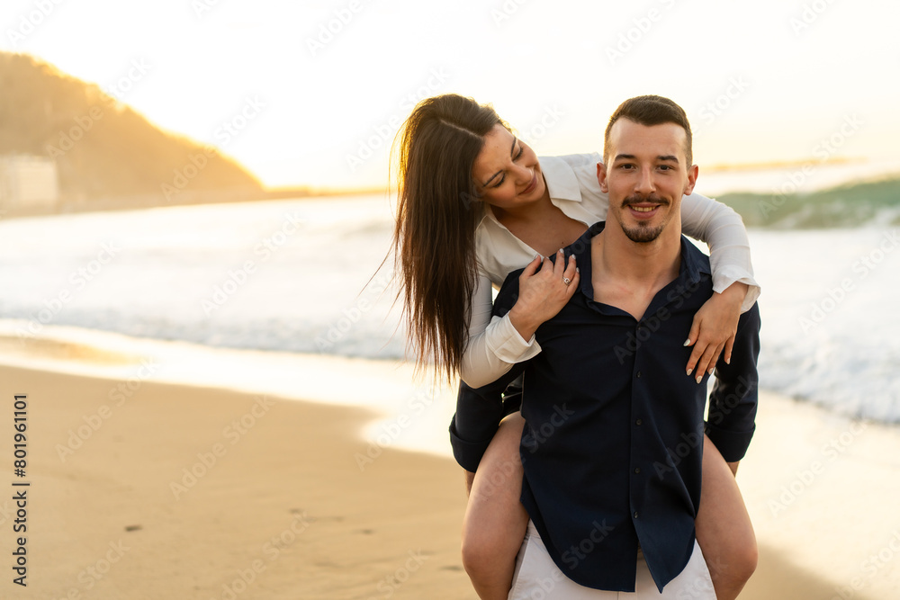 Woman piggybacking her boyfriend on the beach