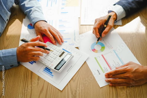 Desk-bound businessman calculates figures, verified accounts, and collaborates in discussions. Proficient in using calculators, aiding each other, and managing annual tax accounts in the audit office photo