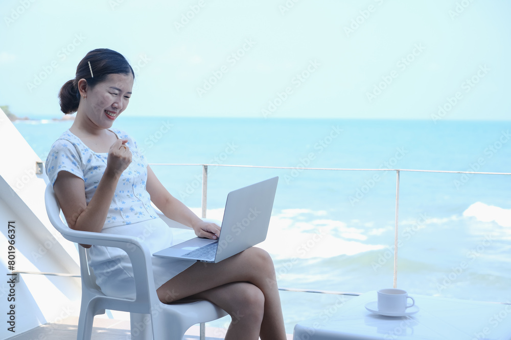 Young asia woman playing laptop computer on tropical beach