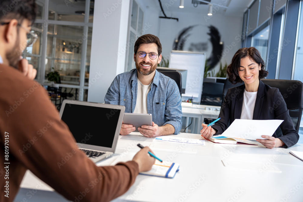 Group of coworkers with laptop having meeting in office Group of coworkers with laptop having meeting in office