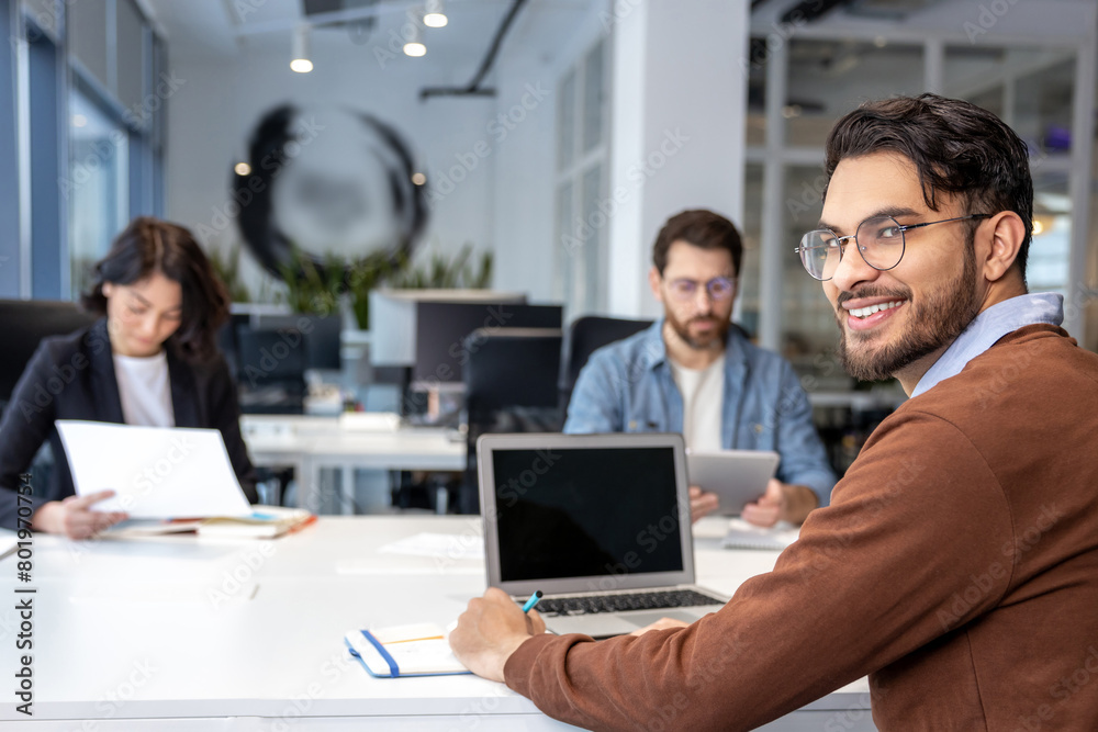 Group of coworkers with laptop having meeting in office