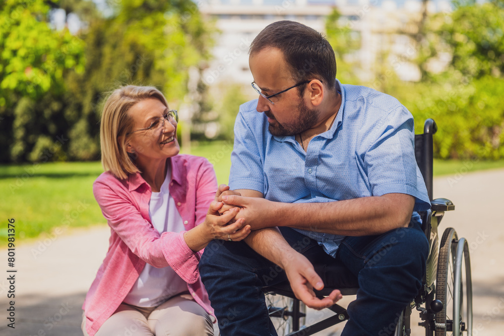 Naklejka premium Man in wheelchair is spending time with his friend in park.