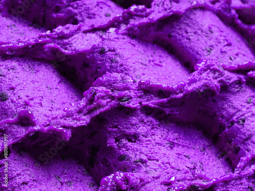 Frozen Lavender flavour gelato - full frame detail of sorbet. Close up of a violet surface texture of Ice cream filled with pieces of mixed flowers.