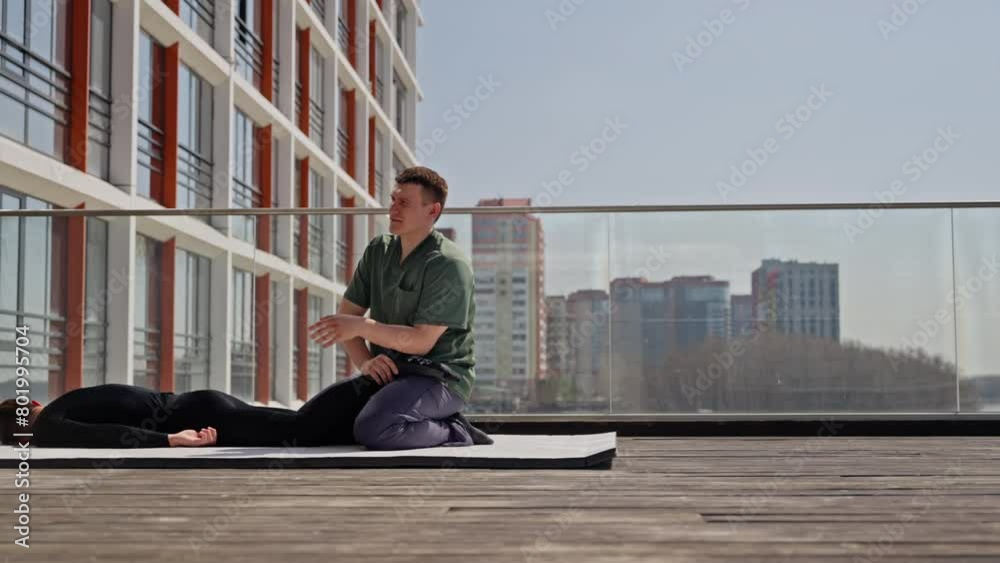 Physical therapist instructing patient in black attire on leg stretching exercise against city background Physical therapist instructing patient in black attire on leg stretching exercise against city background