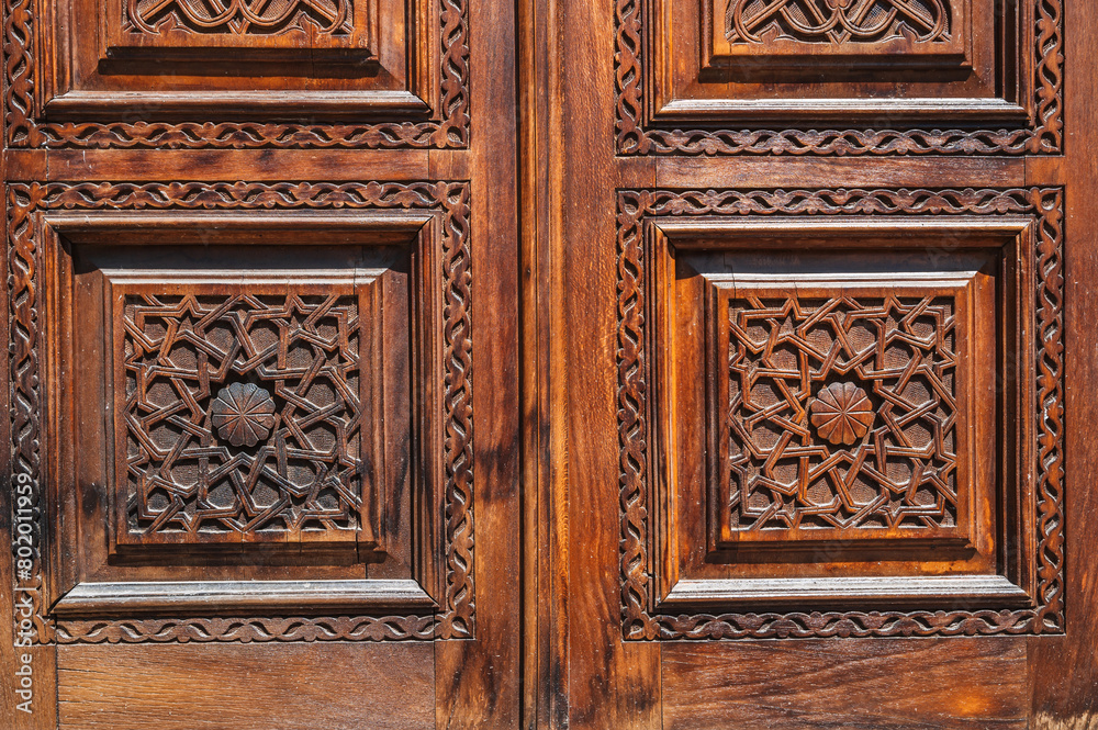 Oriental tajik Islamic kandakori patterns arabesque ornament on an old wooden carved door in Tajikistan close-up