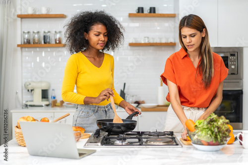 Diversity young happy love LGBT  LGBTQ caucasian and african family lesbian couple woman cook vegan food healthy eat with fresh vegetable salad in kitchen at home  pride  rainbow.Lgbt lesbian couple