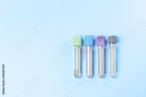 Four tubes of different colors are lined up on a blue background. The tubes are all different sizes and shapes