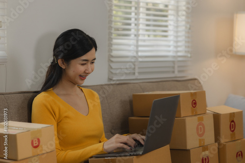 A beautiful female entrepreneur of an online small business is proudly working in her personal warehouse with boxes full of merchandise, Verify customer information before delivering the product