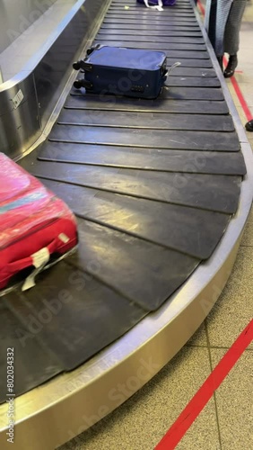 A lot of suitcases and luggage on a moving conveyor belt at the airport. The passengers waiting their baggage at hall