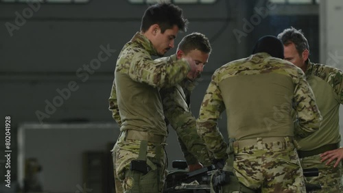 Soldiers standing around weapons indoors
