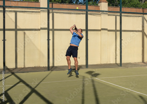 Athletic Man Performing High Jump Serve in Padel Tennis © Alejandro