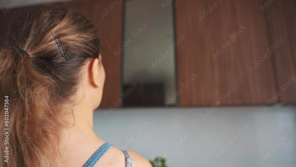 unrecognizable happy woman washes glass mirror in modern kitchen facade furniture, solution is sprayed onto surface, female hand close-up wipes away dirt. Girl enjoy House cleaning back rear view 4k unrecognizable happy woman washes glass mirror in modern kitchen facade furniture, solution is sprayed onto surface, female hand close-up wipes away dirt. Girl enjoy House cleaning back rear view 4k