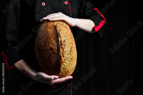 Fresh sourdough bread in the hands of a baker. Top view. © Yaruniv-Studio