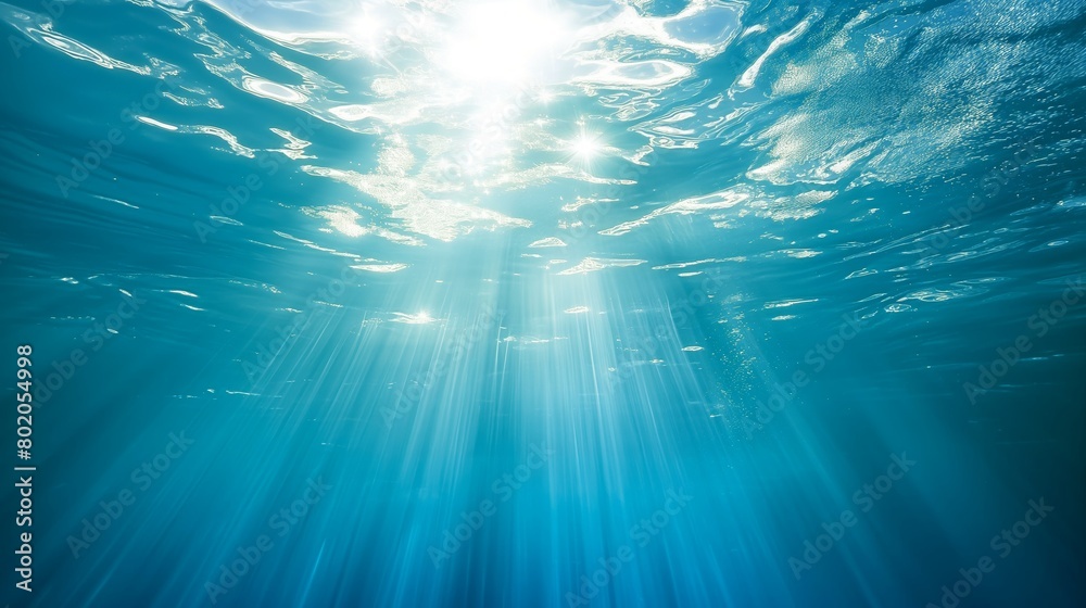Fototapeta premium Sun shining through water creates electric blue hues underwater