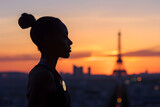 Dramatic silhouette of a gymnast with an Olympic medal hanging around their neck, standing before the Parisian skyline at dusk
