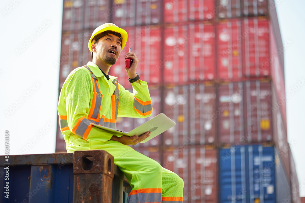 worker or engineer talking on walkie talkie and holding laptop computer in containers warehouse storage worker or engineer talking on walkie talkie and holding laptop computer in containers warehouse storage