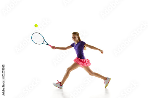 Focused on game young girl, tennis player in vibrant uniform ready to serve ball to opponent against white studio background. Concept of professional sport, movement, tournament, action. Ad © Lustre