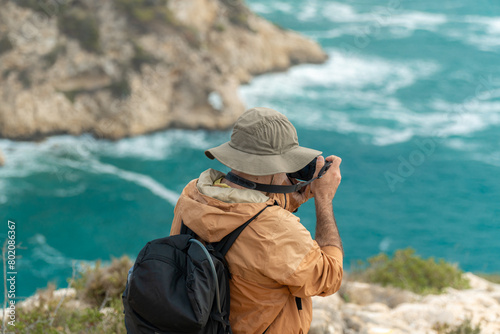 Unrecognizable hiker taking photos to the sea with a professional camera.