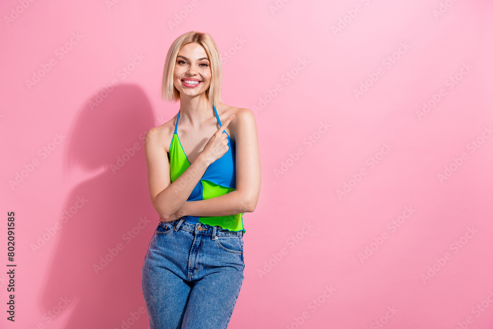 Photo of lovely cheerful girl with bob hairdo dressed colorful tank indicating at offer empty space isolated on pink color background