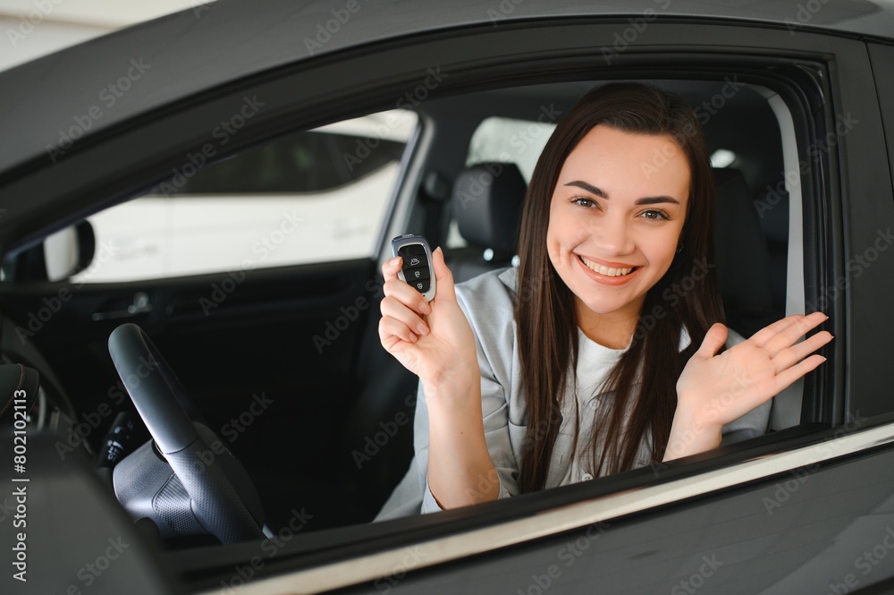 Happy owner sitting inside her car holding keys