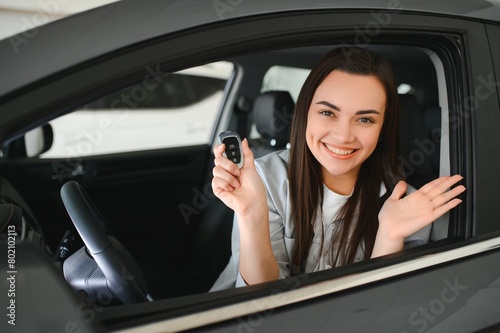 Happy owner sitting inside her car holding keys