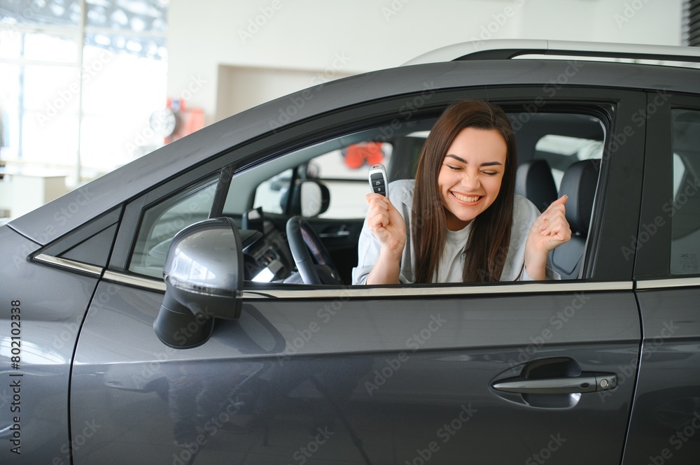 Happy owner sitting inside her car holding keys Happy owner sitting inside her car holding keys