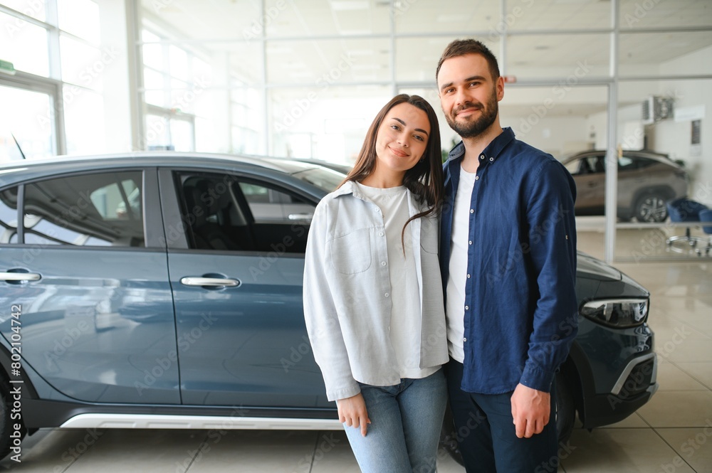 Happy young couple chooses and buying a new car for the family. Visitting the dealership Happy young couple chooses and buying a new car for the family. Visitting the dealership