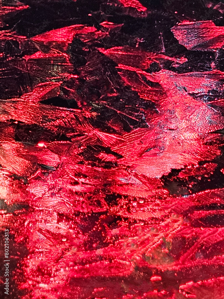 Red abstract background texture of ice crystals on glass with a red light behind it.