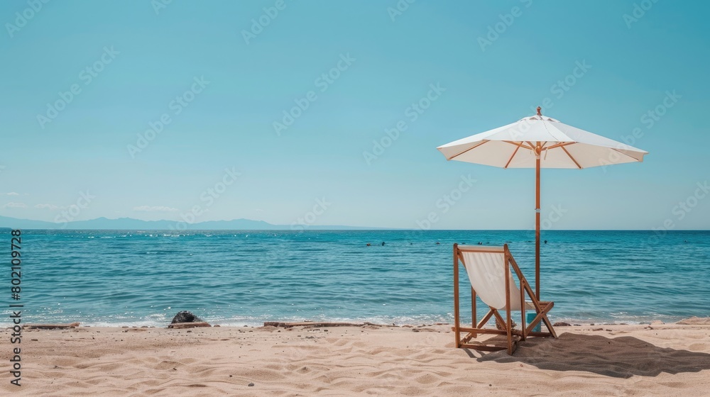 A chair and an umbrella provide shade on the sandy beach, with the azure sky reflecting in the crystal clear water of the oceanic coastal landforms AIG50