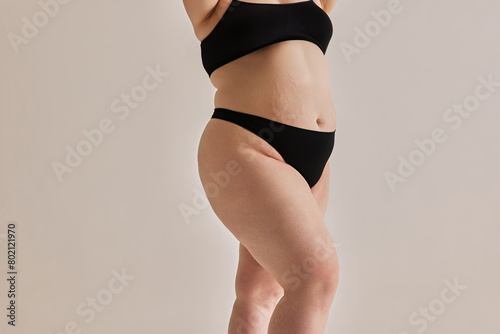 Beauty and uniqueness of natural body shapes. Cropped image of oversized feme body in nerdwear against grey studio background. Concept of natural beauty, body positivity, care, acceptance photo