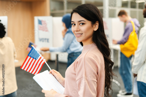 Fotografie Happy Asian woman, American citizen holding American flag and ballot paper stand